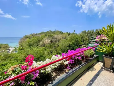 a balcony with flowers and the ocean in the background at Kata Sea View Sanctuary in Kata Beach