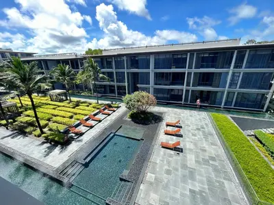 an office building with a swimming pool and lounge chairs at 2 Bedroom Beachfront Apartment With Sea Views in Mai Khao Beach