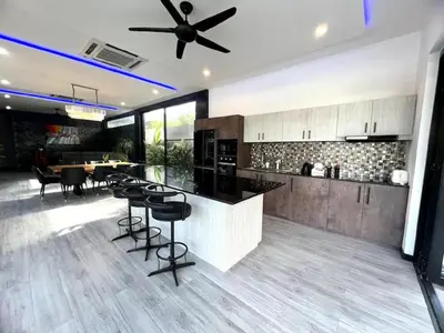 a kitchen with a bar with chairs and a ceiling fan at Villa Christal - Modern 3 bedrooms with pool in Ban Saiyuan (1)