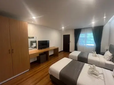 a hotel room with two beds and a desk with a television at MYP Cherngtalay in Phuket Town