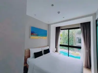 a white bedroom with a bed and a large window at 1 Bedroom Pool view at Diamond Condo, Bangtao in Bang Tao Beach