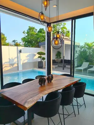 a dining room with a wooden table and chairs and a pool at Bangtao Luxury Pool Villa - Prymana in Phuket Town