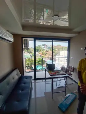 a man standing in a living room with a table and a couch at Rawai beach condominium Phuket in Nai Harn Beach