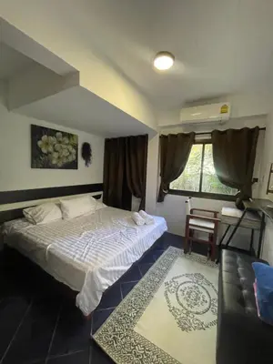 a bedroom with a bed and a chair and a window at Aisawan Resort villa in Surin Beach