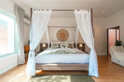 a bedroom with a canopy bed with white curtains at Rosemary Villa 4 bedrooms with Pool near BangTao Beach in Bang Tao Beach