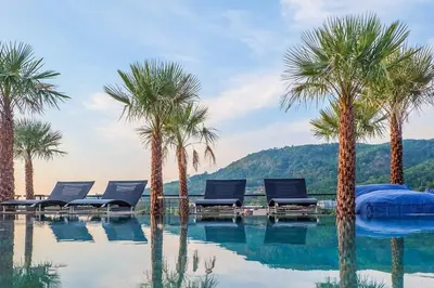 a swimming pool with palm trees and lounge chairs at Tropics Kamala Hill View Suite CTG D707, near Beach and Fantasea in Kamala Beach
