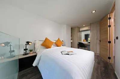 a bedroom with a large white bed with orange pillows at Pool Access Utopia Loft, just 10 min from Nai Harn Beach, UTL A116 in Rawai Beach