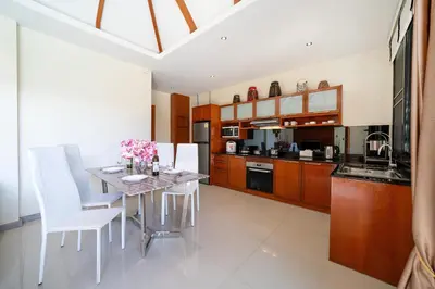 a kitchen with a dining table and white chairs at Private 2BR Pool Villa 2D03 in Gated Residence Rawai VIP Villas in Rawai Beach