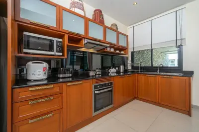 a kitchen with wooden cabinets and a microwave at Private 2BR Pool Villa 2D15 in Gated Residences Rawai VIP Villas near Kids Park in Rawai Beach