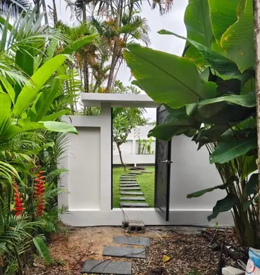 a pivot door in a garden with plants at Pool Villa - 3 Bedroom- Walking to Bangtao Beach, Restaurants and Supermarkets in Bang Tao Beach