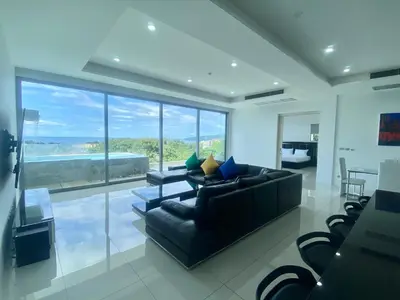 a living room with a black couch and a large window at The View Luxury Condominium Karon in Kata Beach