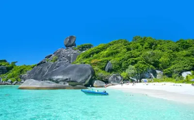 a boat in the water next to a beach at Patong Vacation Condos by Pam - 28 SQM modern condos with private bathroom, kitchen, King Bed, free WiFi and 65 inch smart TC in Patong Beach