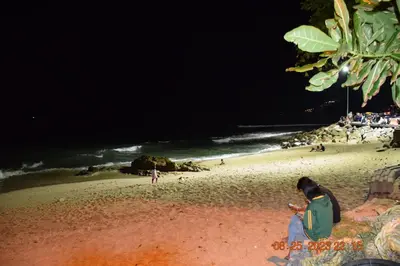 a person standing on a beach at night at Kalim Residence in Patong Beach