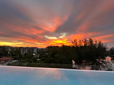 a sunset over a swimming pool with a sky at Laguna Skypark, 2 bedrooms & large terrace with golf view in Phuket Town