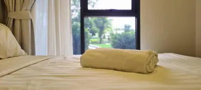 a towel sitting on top of a bed with a window at Laguna Skypark, 2 bedrooms & large terrace with golf view in Phuket Town