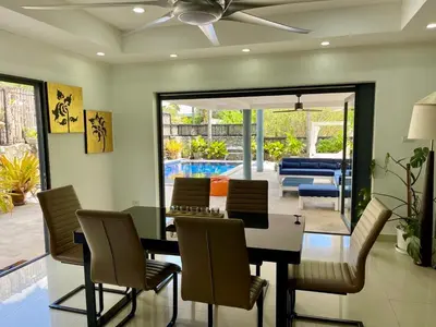 a dining room with a table and chairs and a pool at Kata Vista Luxury Modern 4BR Private Pool Villa in Kata Beach