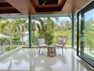 a screened porch with two chairs and a table at Kata Vista Luxury Modern 4BR Private Pool Villa in Kata Beach