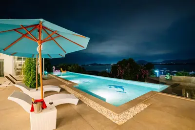 a blue swimming pool with a blue umbrella at Phuket 4-6 Bedroom Seaview Villa Infinity 25mPool In-Villa Dining & Butler Gym in Thalang