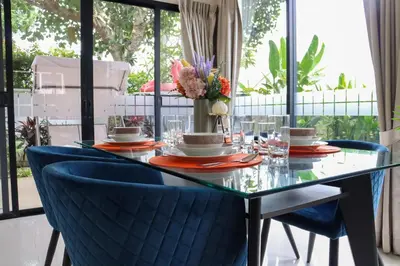 a glass table with blue chairs and flowers on it at Happy House in Laguna Park in Laguna Phuket