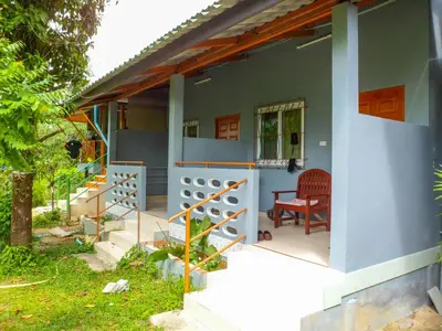 a blue house with a red chair on the porch at Bonus Bungalow in Chalong