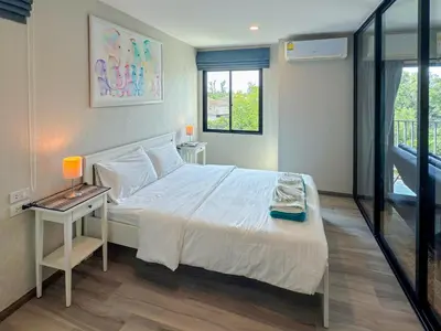 a bedroom with a bed and a table with a lamp at The Title Residencies Naiyang F by Mill in Nai Yang Beach