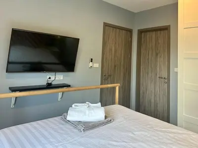 a room with a bed with a flat screen tv on the wall at The Title Residencies Naiyang F by Mill in Nai Yang Beach