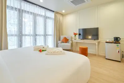 a white bedroom with a large bed and a tv at Hawa House Phuket in Phuket Town