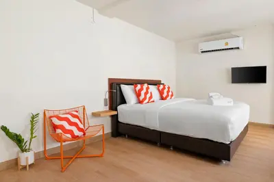 a bedroom with a large bed and a chair at Horange Phuket Town in Phuket Town