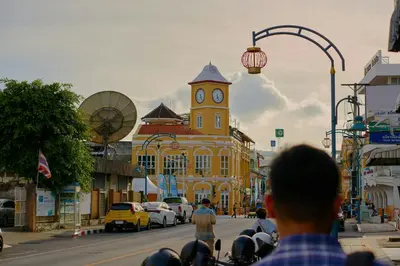 a yellow building with a clock tower on a street at Horange Phuket Town in Phuket Town