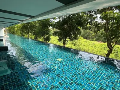 a blue swimming pool with a view of a field at Zcape X2 boat avenue by sahana in Bang Tao Beach