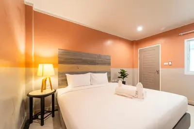 a large white bed in a room with orange walls at Nature's Hideaway by Ratana, Rawai in Ban Saiyuan (1)