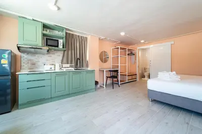a room with a bed and a kitchen with green cabinets at Nature's Hideaway by Ratana, Rawai in Ban Saiyuan (1)