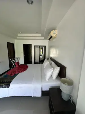 a large white bed with a red blanket on it at The Seashore Kamala Service Apartment in Kamala Beach