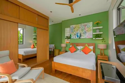 a bedroom with green walls and a bed and a desk at Villa White Skies in Khok Kloi