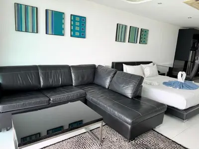 a living room with a black leather couch and a table at Private sea view studio at Twin Sands in Patong Beach