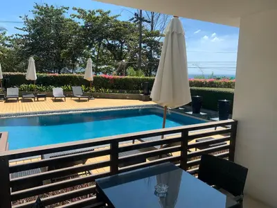 a swimming pool with a table and a umbrella at Pool view studio at Nakalay Palm by Lofty in Kamala Beach
