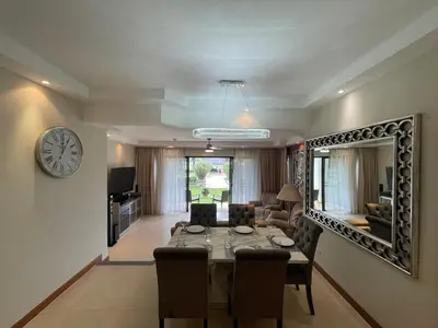 a living room with a table and a clock on the wall at Allamanda Laguna 2 BR c выходом к бассейну in Phuket Town