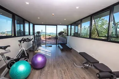 a gym with exercise equipment in a room with windows at DLUX Condominium Chalong Phuket in Ban Klang