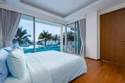 a bedroom with a bed with a view of the ocean at WEG Elite Beachfront in Phuket Town