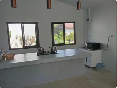a kitchen with a counter and two windows at Rapina House in Mai Khao Beach