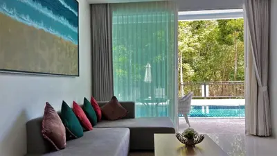 a living room with a couch and a view of a pool at Kamala Falls Seaview 2 bedroom in Kamala Beach