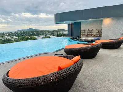 a swimming pool with orange chairs and a swimming pool at Duplex in a 5 star hotel La Vita in Phuket Town