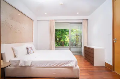 a bedroom with a white bed and a window at Modern Beachfront Apartment Naithon Beach in Nai Thon Beach