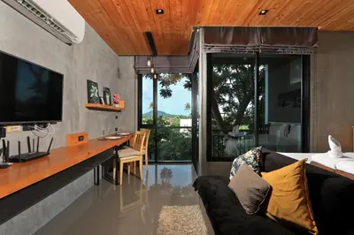 a living room with a couch and a desk with a television at 1bdr Apartment near NaiHarn beach by Capital Pro in Phuket Town