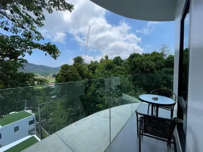 a glass balcony with a table and a view at Utopia Naiharn by Fred&Com Phuket in Rawai Beach