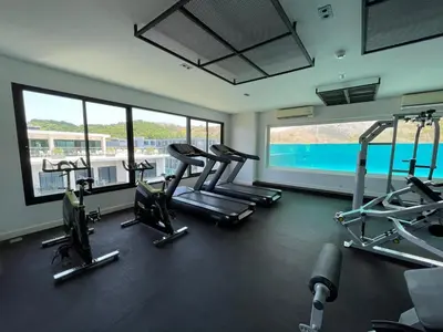 a gym with cardio equipment in a building with windows at Utopia Naiharn by Fred&Com Phuket in Rawai Beach