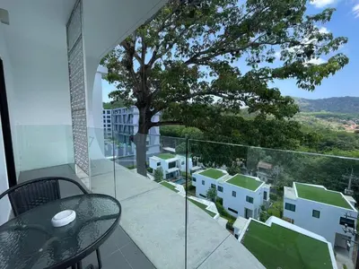 a balcony with a table and a tree at Utopia Naiharn by Fred&Com Phuket in Rawai Beach