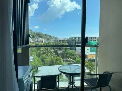a balcony with a table and chairs and a view of the city at Top floor apartment at Aristo by Lofty in Surin Beach