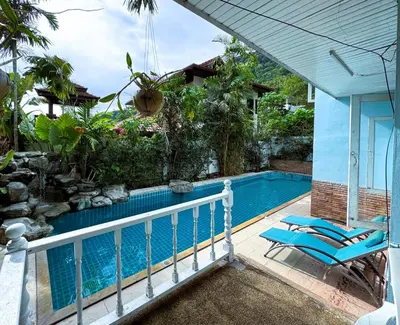 a swimming pool with blue chairs next to a house at Mountain View Villa Kamala in Kamala Beach
