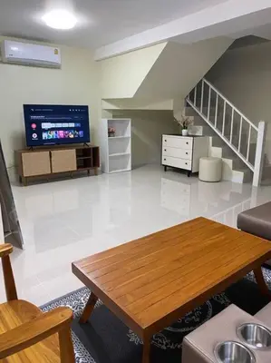 a living room with a table and a staircase at Kata beach townhouse in Kata Beach